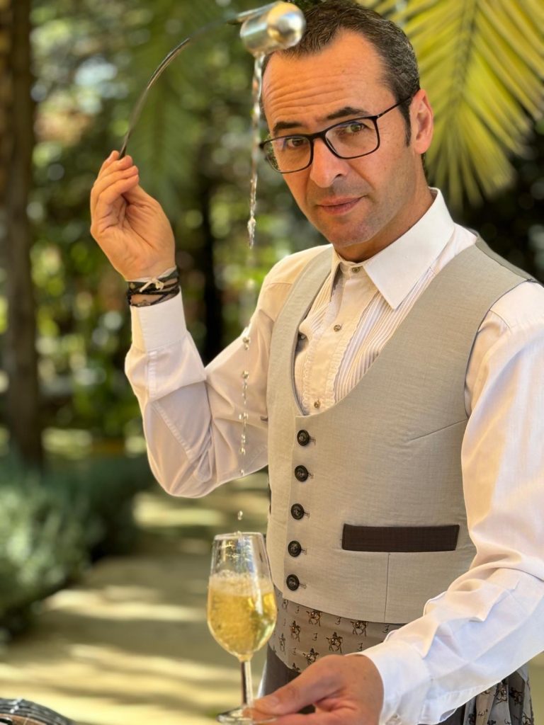 José Manuel Ruz, venenciador, sirviendo vino espumoso con la venencia al aire libre
